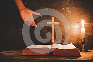 Open Holy Bible and candle on a old oak wooden table.