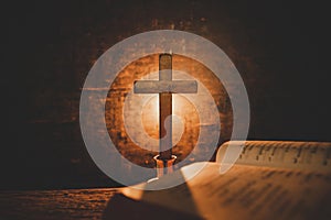 Open Holy Bible and candle on a old oak wooden table. Beautiful gold background.