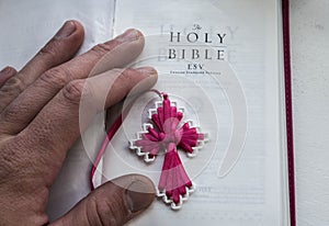 A open holy bible with a cross and man hand on a white background