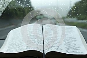 Open Holy Bible in Psalm 121 on stormy day. Blurred background with expressway and cars.