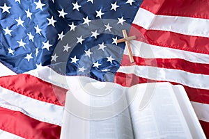 Open Holy bible and Wooden cross over American flag background