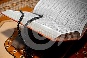 An open The holy Quran with black Tasbeeh.