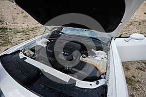 Open hood of white muscle car, engine