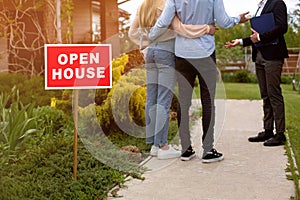 OPEN HOUSE sign and realtor showing potential buyers property for sale, outside. Cropped view