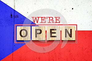 We are open. The inscription on wooden blocks against the background of the flag of the Czech Republic. Business