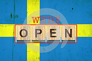 We are open. The inscription on wooden blocks against the background of the flag of Sweden. Business