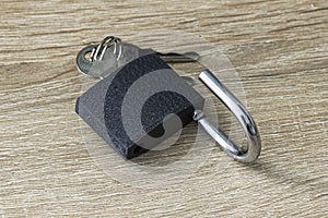 Open iron padlock with keys in the keyhole on the wooden surface concept prohibition security restriction
