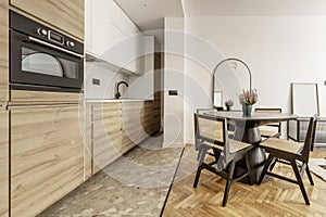 Open kitchen in a loft-style home with white oak furniture, circular black wooden dining table and matching chairs