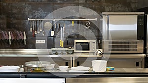 Open kitchen of a modern restaurant with refrigerators and ovens, cooking utensils, knives, whisks, pots