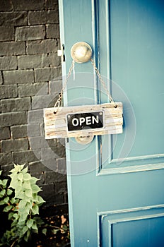 Open label hanging on blue door in garden