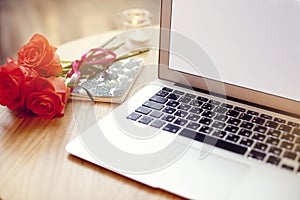 Open laptop computer with blank space for layout on a wooden table in cafe bar, St. Valentines flowers, note book during coffee br