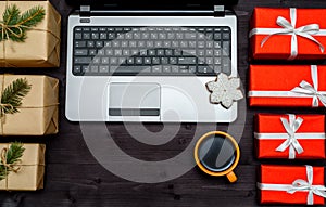 Open laptop computer, Christmas presents and gingerbread cookies on dark wood background, copy space. Top view, flat lay