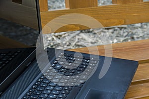 Open laptop computer on a wooden bench