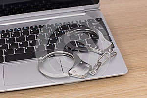 Open laptop with locked handcuffs on the keyboard