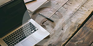 Open laptop , pencil and notebook on rough weathered wooden surface, with copy space for text.