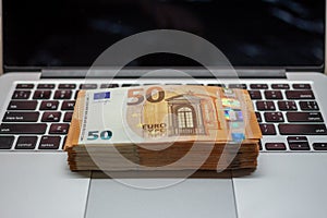 Open laptop and stacks of money euro banknotes