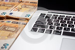 Open laptop and stacks of money euro banknotes