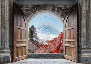 Open large wooden door with mount Fuji-san and autumn maple tree in blue sky