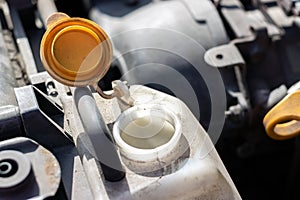 Open lid on an antifreeze tank. Dusty details of a flat-four boxer car engine compartment under the open hood