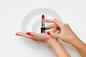 Open lipstick in a woman`s hand isolated on white background. Red nails. Advertisement. Space for text on the background