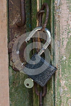 Open lock with a key hanging on an old door