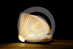 Open magic book with bright pages on a wooden table and black background  with copy space for your text