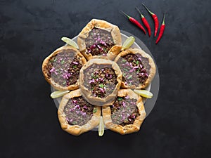 Open meat pies on a black background. Top view.