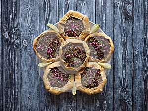 Open meat pies on dark wooden background. Top view