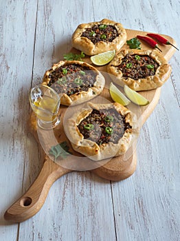 Open meat pies on a wood background. Top view.