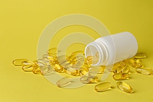 Open medicine bottle with scattered pills on yellow background, space for text