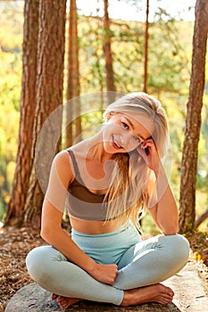 Open-minded smiling woman sits on the ground posing on fresh air photo