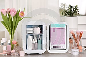 Open mini cosmetics refrigerator and skin care products on table