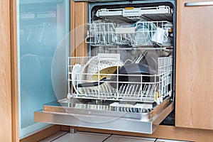 Open modern dishwasher with messy dishes  in the kitchen