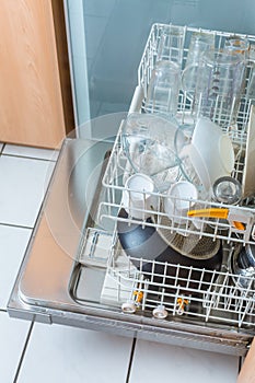 Open modern dishwasher with messy dishes  in the kitchen