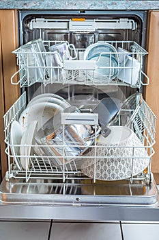 Open modern dishwasher with messy dishes  in the kitchen