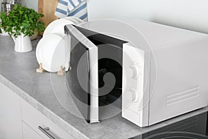Open modern microwave oven on table