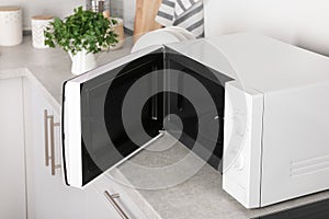 Open modern microwave oven on table