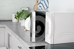 Open modern microwave oven on table