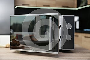 Open modern microwave oven on table