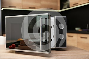 Open modern microwave oven on table
