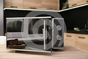 Open modern microwave oven on table