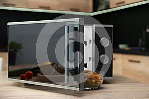 Open modern microwave oven on table