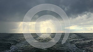 Open North Sea with Dramatic Sky after a Rain Storm. Dark Clouds and Rays of Sunshine. Filmed from the back of a boat.