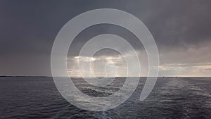 Open North Sea with Dramatic Sky after a Rain Storm. Dark Clouds and Rays of Sunshine. Filmed from the back of a boat.