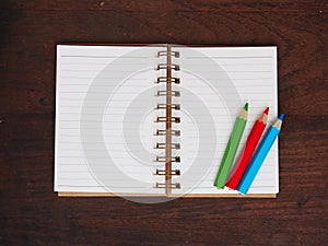 Open note book and color pencil on wooden background