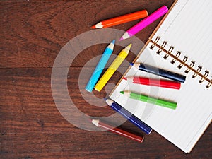 Open note book and color pencil on wooden background