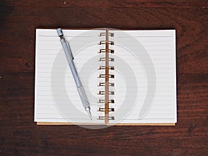 Open note book and pencil on wooden background