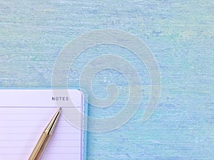 On an open note, a golden pen pointing to a `notes` word, aqua blue background.