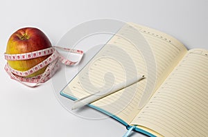 Open notebook with an apple and a centimeter on the table. Copy space