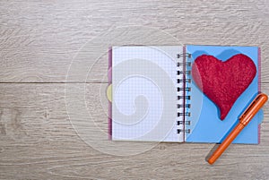 Open notebook with ballpoint pen and red heart of woo